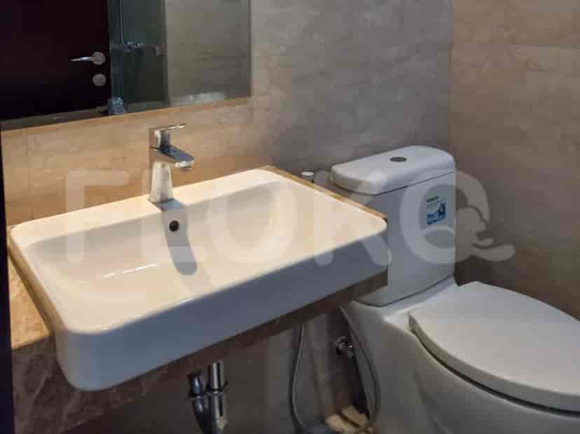 A bathroom with a sink, toilet, and marble-tiled walls.