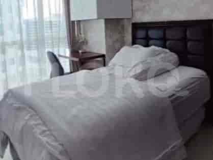 A well-lit bedroom featuring a bed with a black headboard and desk space.