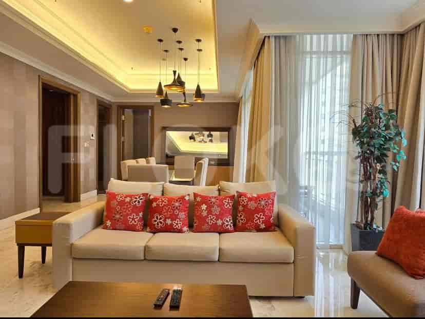 Elegant living room with a beige sofa, floral cushions, and a dining area visible through an archway.