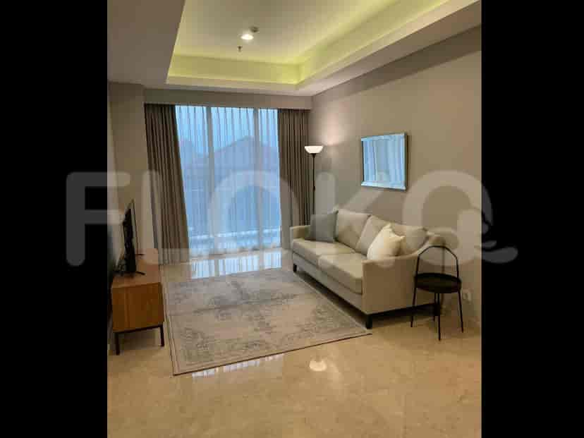 A bright living room with a sofa, rug, television, and large window.