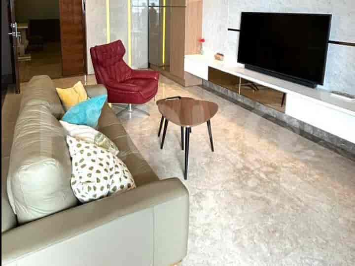 A modern living room with a grey sofa, a red armchair, a triangular coffee table, and a wall-mounted TV.