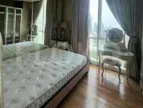 Close-up of the master bedroom showing the bed, a dressing table, and a window with a city view.