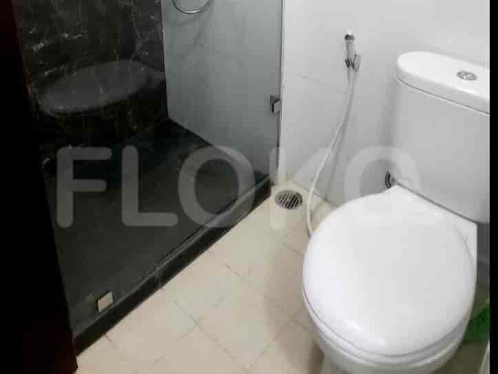 A bathroom with a toilet, shower, and tiled walls.