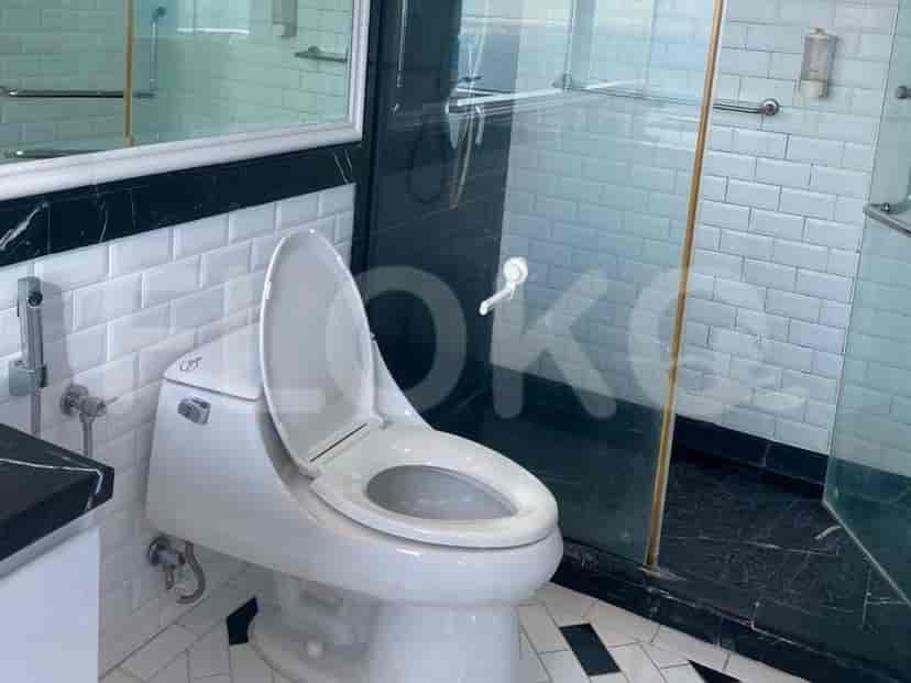 Kamar mandi dengan toilet, area pancuran, dan cermin.