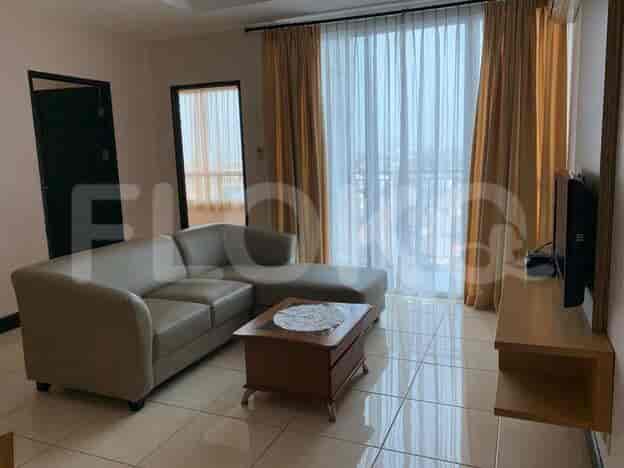 A spacious living room with an L-shaped grey sofa and a large window with curtains.