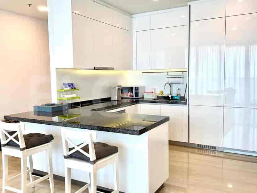 A modern L-shaped kitchen with white cabinets, granite countertops, and bar stools.