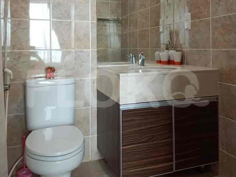 A bathroom with a toilet, a marble-top vanity with dark wood cabinets, and tiled walls.