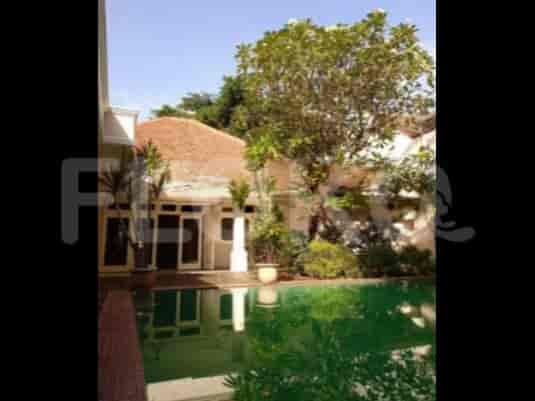 A view of the backyard with a swimming pool, trees, and a small patio.
