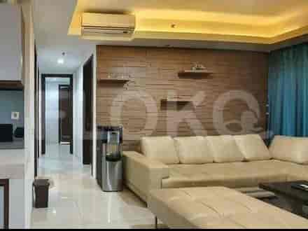 A living room with an L-shaped sofa, and access to a kitchen and hallway.