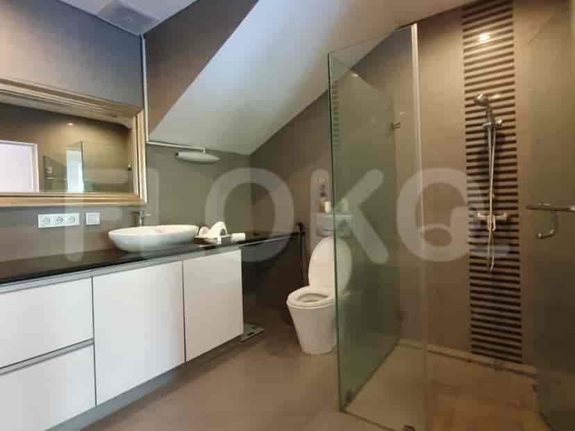 Kamar mandi modern menampilkan meja rias putih dengan wastafel, cermin besar, toilet bergaya barat, dan pancuran tertutup kaca.