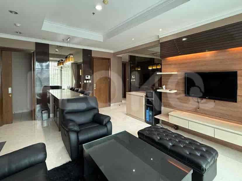 A modern living room featuring a black leather sofa, a glass coffee table, and a TV mounted on a wooden accent wall.