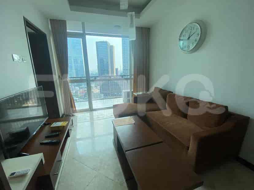 A living room with a brown sofa, coffee table, and a large window overlooking a city.