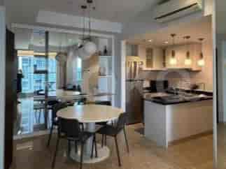 Area ruang makan dan dapur terbuka dengan meja makan bundar, kursi, dan peralatan dapur modern.