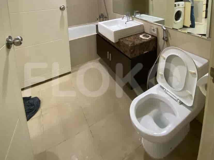 A bathroom with a toilet, sink, and bathtub, featuring beige tiled walls and floor.