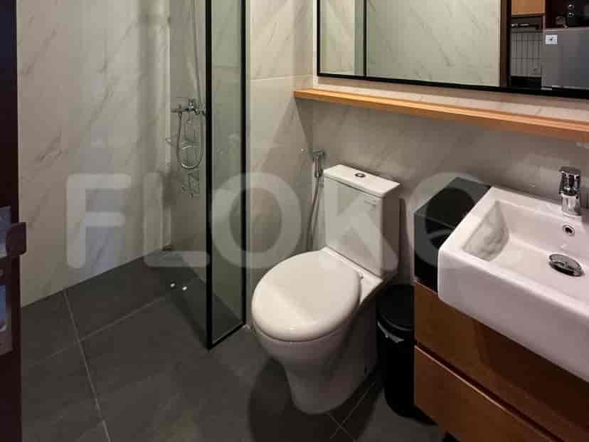 Modern bathroom with a toilet, sink, and glass shower.