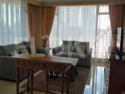 A living room featuring a grey sectional sofa, a wooden coffee table, and large windows with sheer and orange curtains.