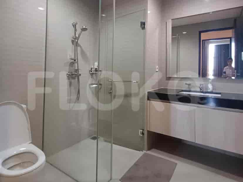 Kamar mandi kontemporer yang menampilkan pancuran berkaca, wastafel, dan toilet.
