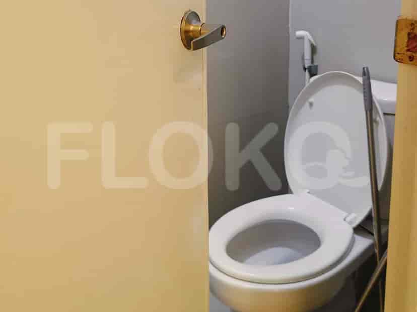 Kamar mandi dengan toilet, pintu, dan pel.