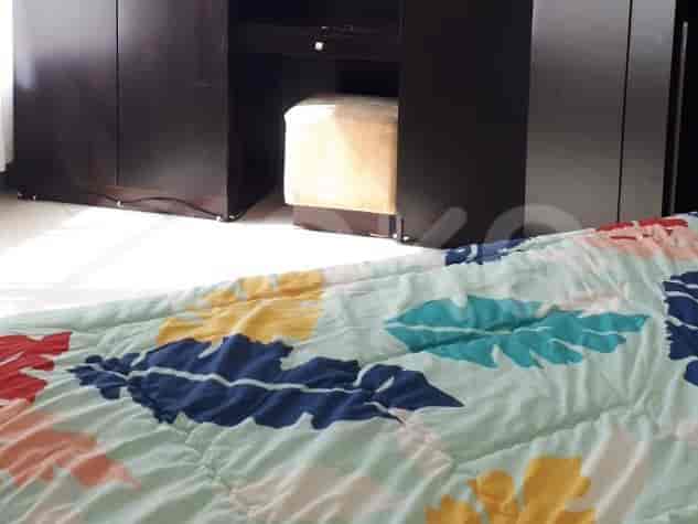 Bedroom with a bed featuring a colorful quilt and a dark brown wardrobe.