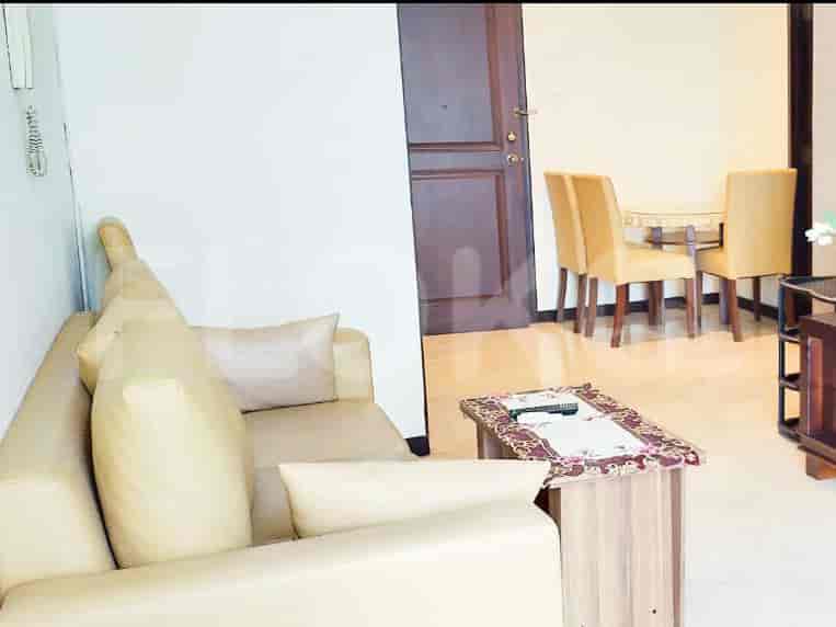 Ruang tamu dengan sofa krem, meja kopi, dan area makan.