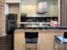 A modern kitchen with a breakfast bar, stools, and appliances.