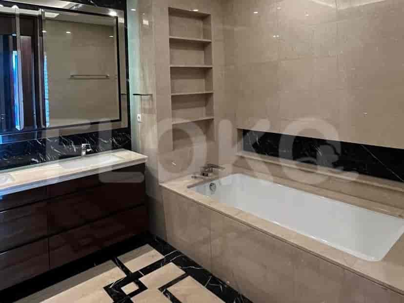 A luxurious bathroom with a bathtub, double vanity, marble tiles, and a large mirror.