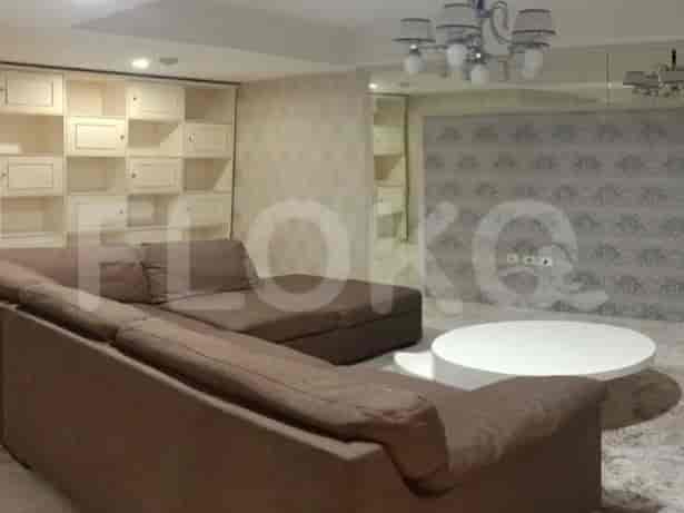 A spacious living room with a large sectional sofa, built-in cabinets, a round coffee table, and decorative wallpaper.