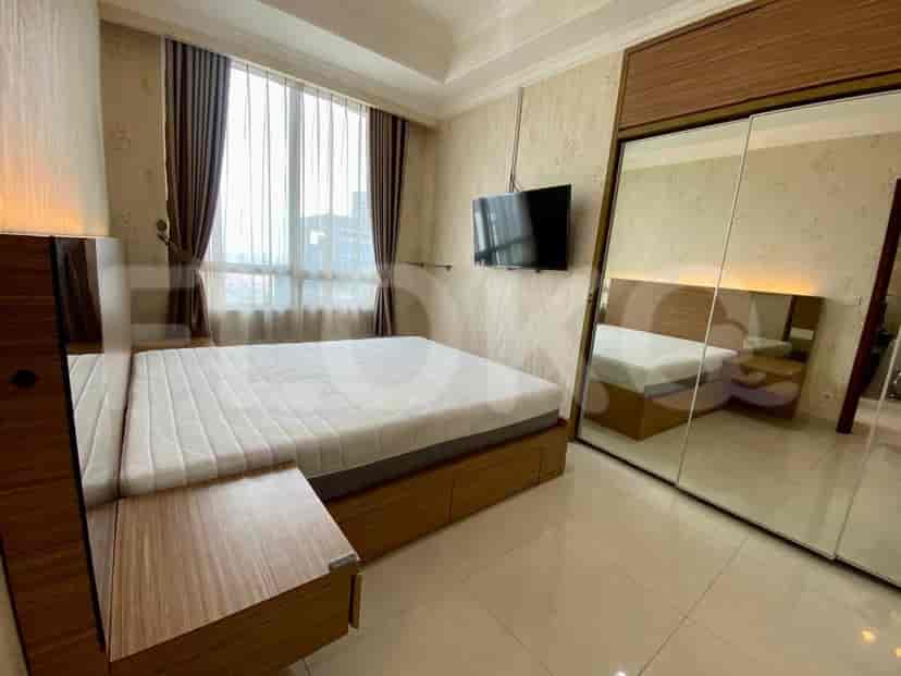 A bedroom with a queen-size bed, a wall-mounted TV, and a large mirrored wardrobe.