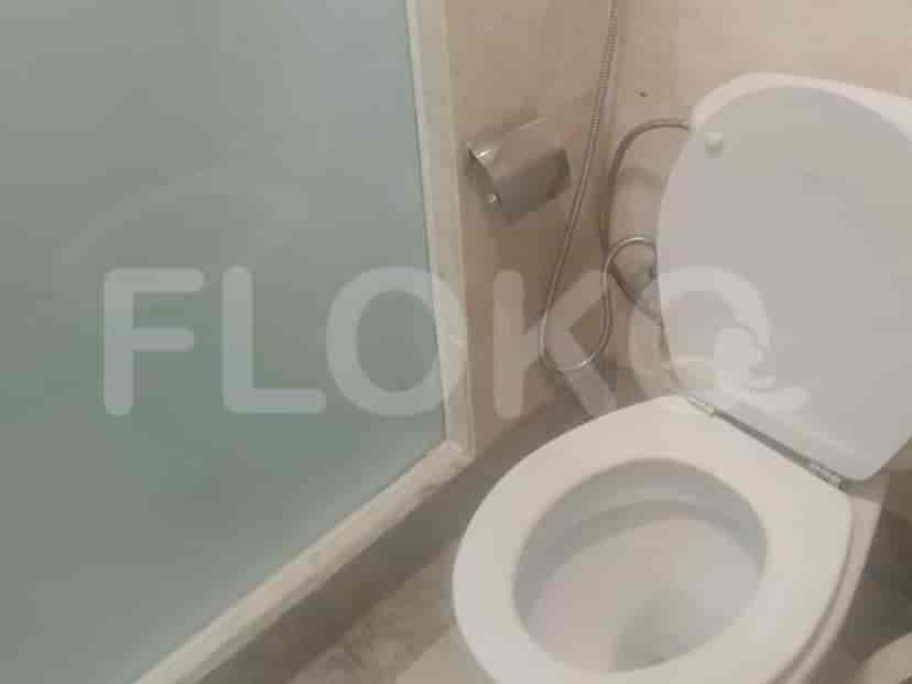 A bathroom with a toilet and a frosted glass partition.