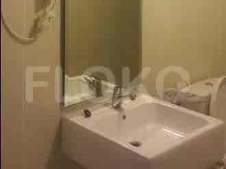 A bathroom with a white sink, faucet, mirror, and toilet.