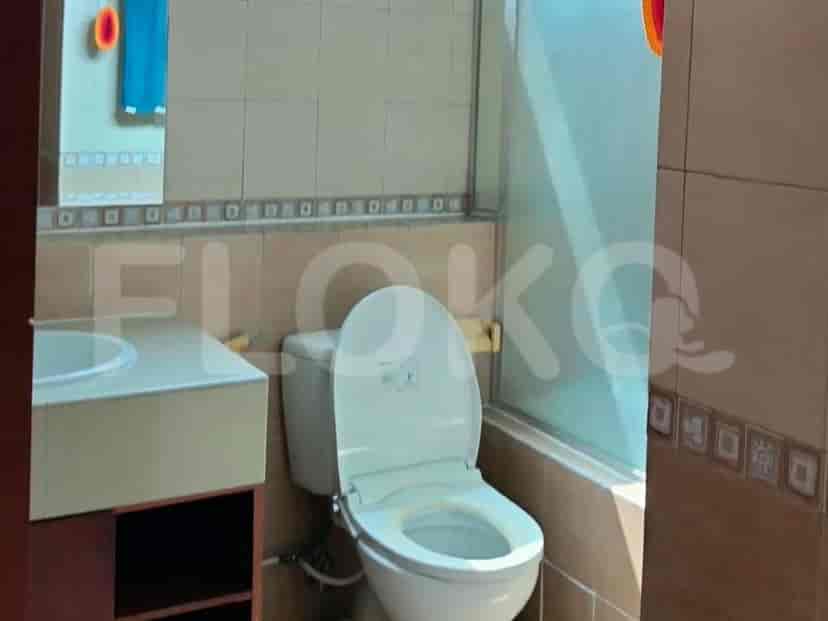 Sebuah kamar mandi dengan toilet, wastafel, dan area shower dengan pintu kaca.