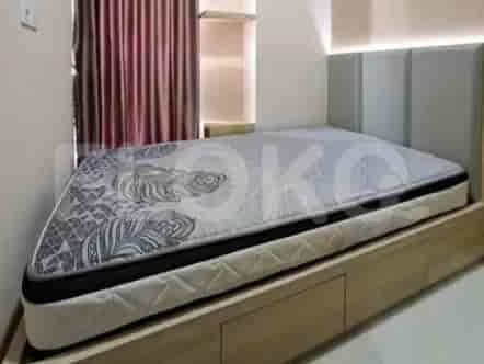 A close-up of a single bed with a patterned mattress in a room with wooden accents.