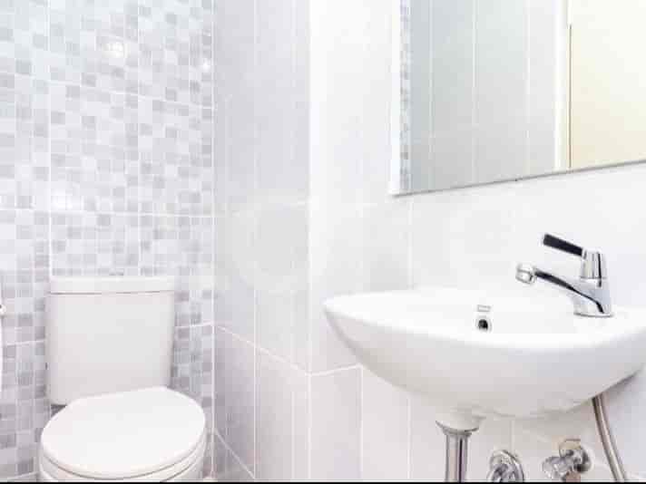 A clean bathroom with a sink, toilet, and tiled walls.