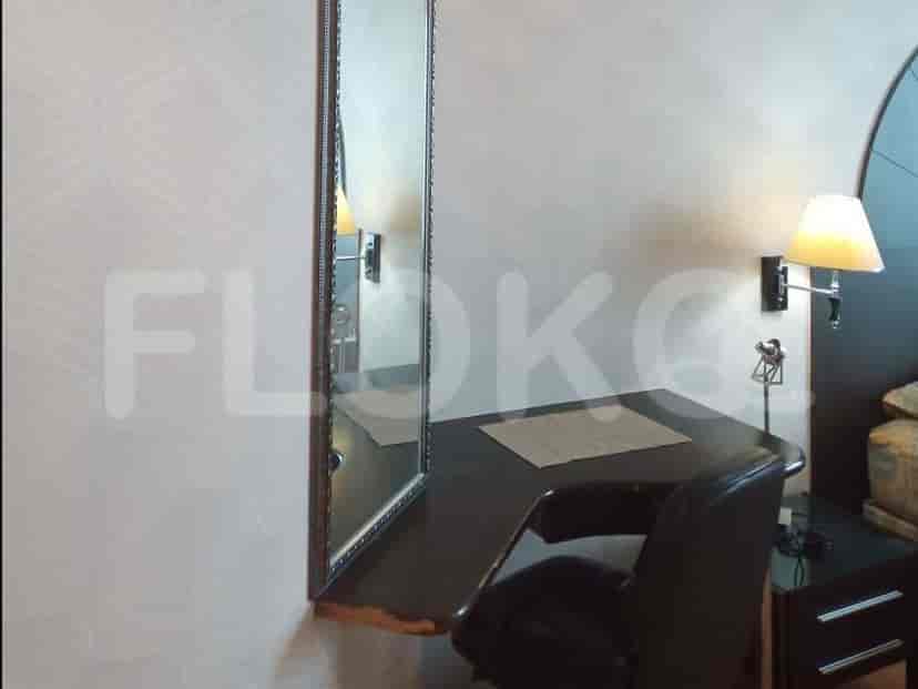 A dressing area with a desk, chair, and mirror, adjacent to a bedroom.