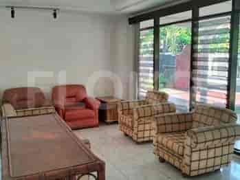 A seating area with comfortable armchairs and a coffee table, adjacent to large windows with blinds.