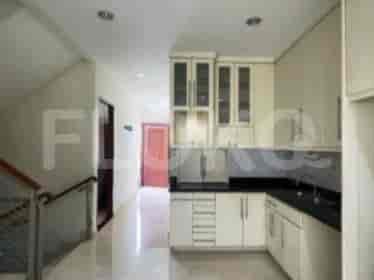 A kitchen with white cabinets, a black countertop, and a staircase leading to the upper floor.
