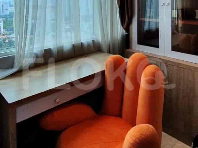 A quirky study area with an orange hand-shaped chair and a wooden desk by a large window.