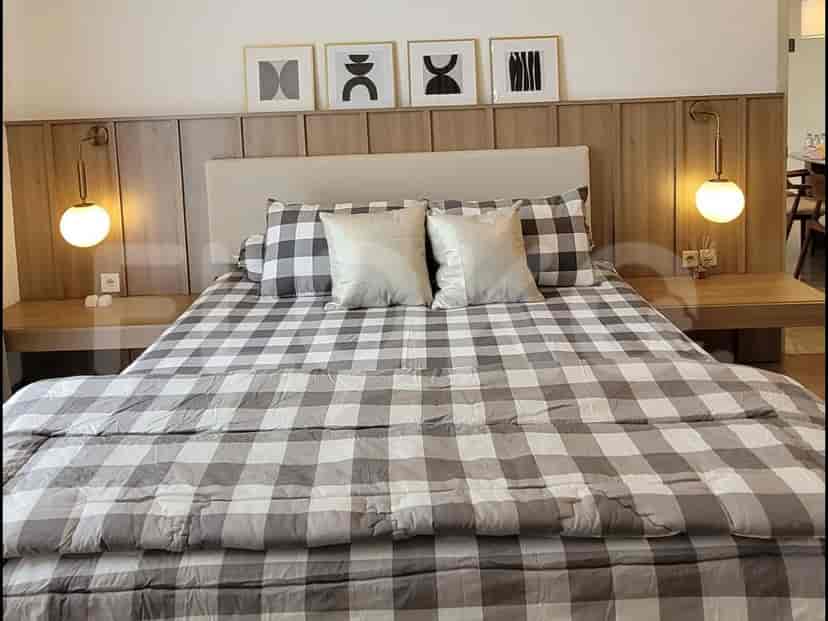 Sebuah kamar tidur utama dengan tempat tidur ukuran king menampilkan selimut kotak-kotak abu-abu dan putih serta dua meja samping tempat tidur.