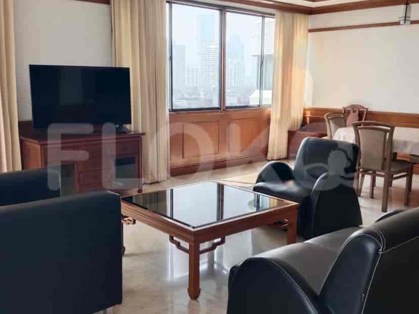 A living room with a television, a coffee table, seating, and a large window overlooking a city.