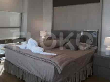 A bedroom with a king-size bed, plush bedding, bedside tables with lamps, and large windows.