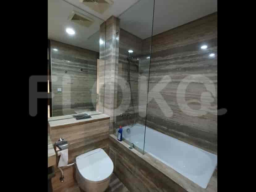 A modern bathroom with a bathtub, toilet, and a vanity with a large mirror.