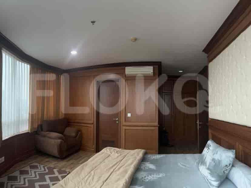 Bedroom with wooden paneling and large windows.
