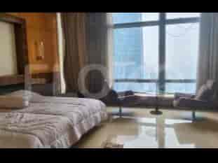 A bedroom with a large bed, two chairs, and a large window overlooking a city skyline.