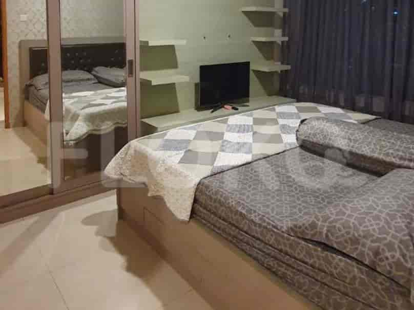A bedroom with a bed, mirror closet, and television.