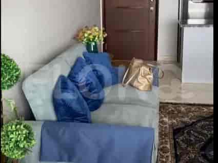 A living room with a grey sofa, blue pillows, and a decorative floral arrangement.