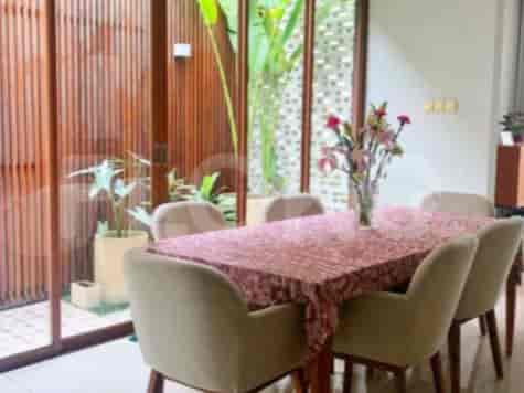 A dining room featuring a rectangular dining table with chairs and a view of a landscaped exterior.