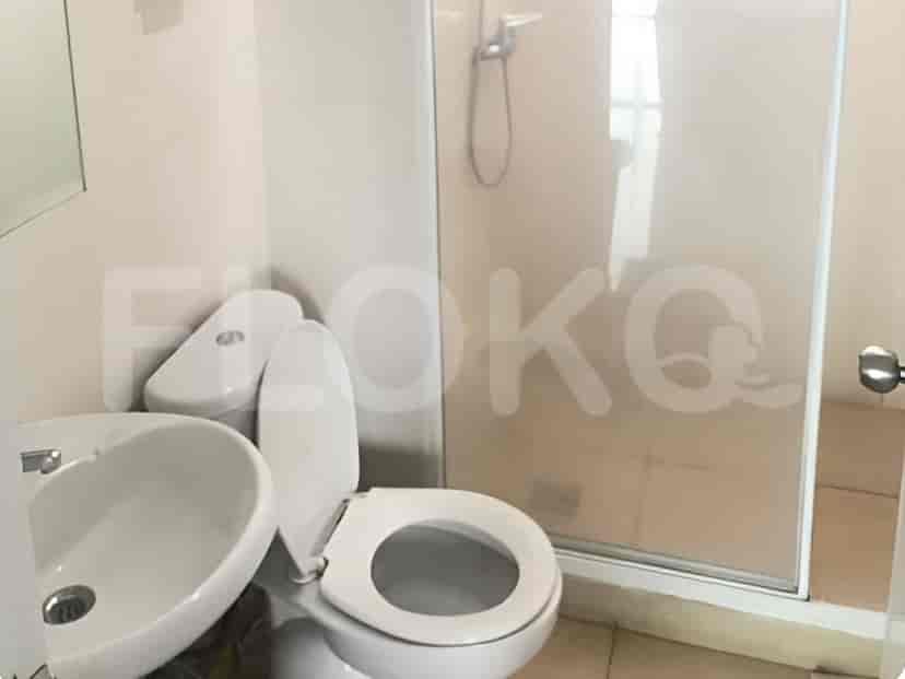 Sebuah kamar mandi dengan wastafel, toilet, dan pancuran berbingkai kaca.