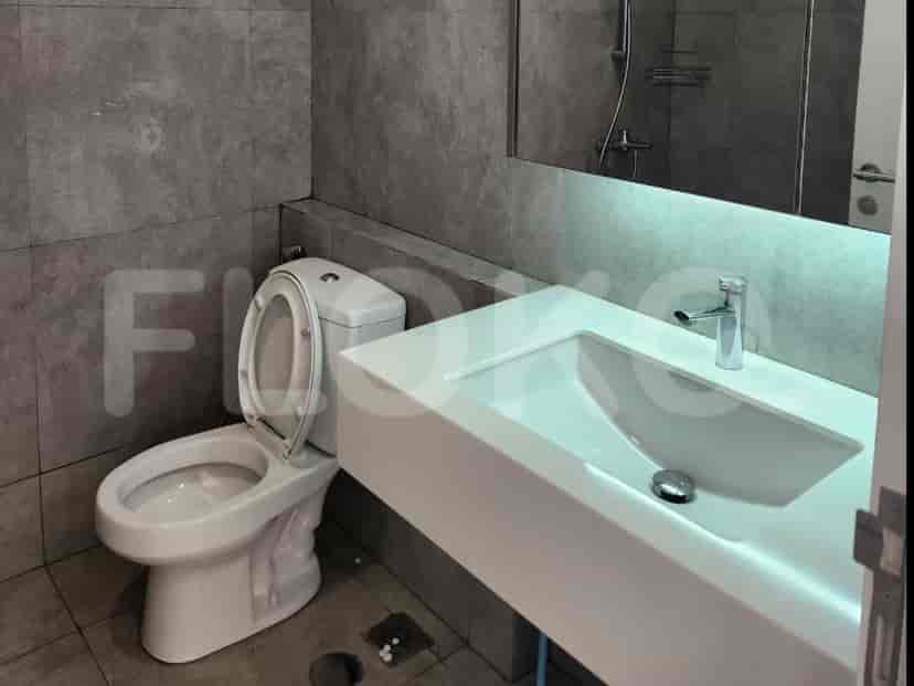 A contemporary bathroom with a white sink, a toilet, and gray tiles.