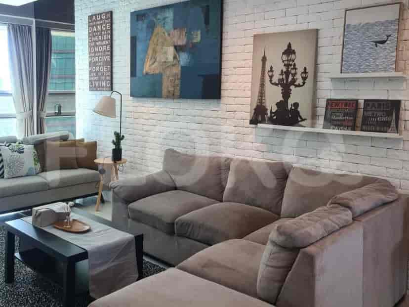 Another view of the living room with a sofa, artwork, and a view of the dining area.