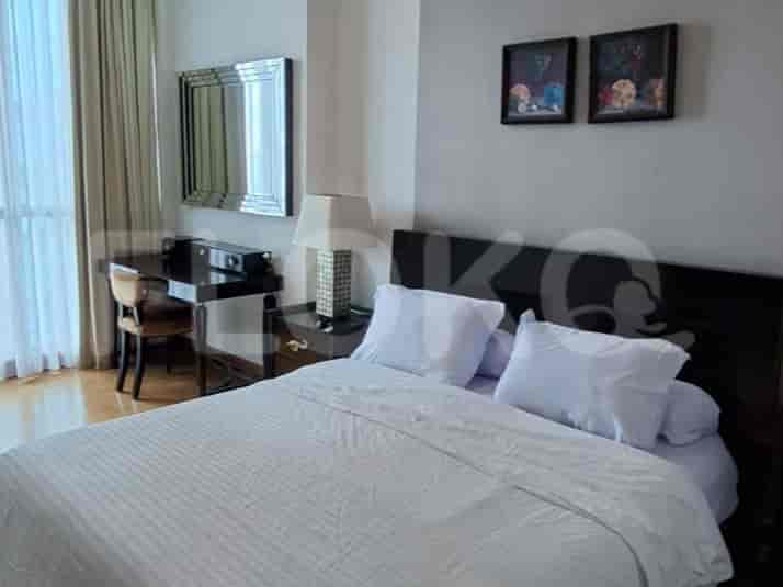 A master bedroom with a large bed, a dressing table, and a mirror.